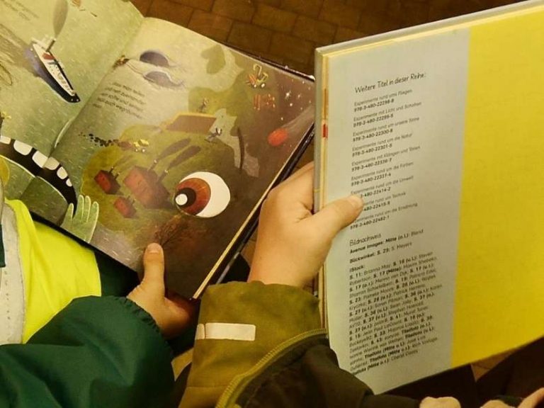 Aufgeschlagene Kinderbücher in Kinderhänden beim Lesen