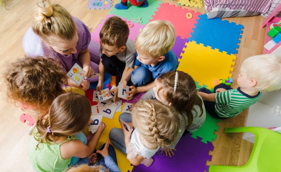 Kinder sitzen mit Erziherin im kreis und spielen